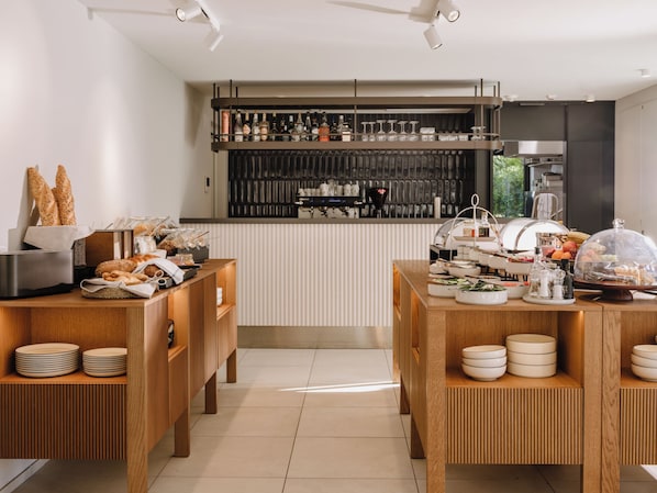 A modern kitchen with wooden cabinetry, a built-in espresso machine, and a variety of food items on the counter.