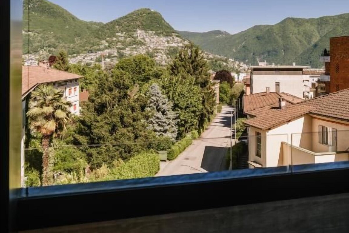 A view from a window overlooking a hillside with buildings and greenery.