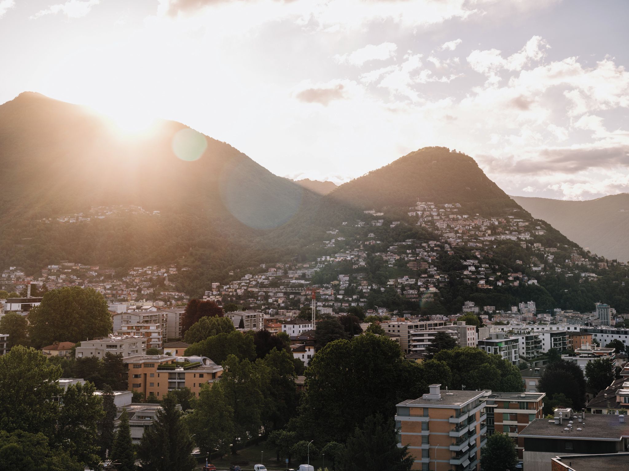 Paisagem urbana com uma montanha ao fundo, edifícios com varandas e céu claro.