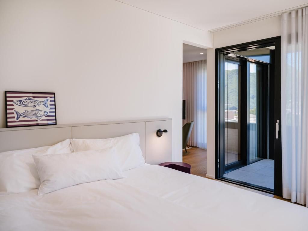 Une chambre d’hôtel avec un lit, un tableau et une porte-fenêtre coulissante donnant sur un balcon.