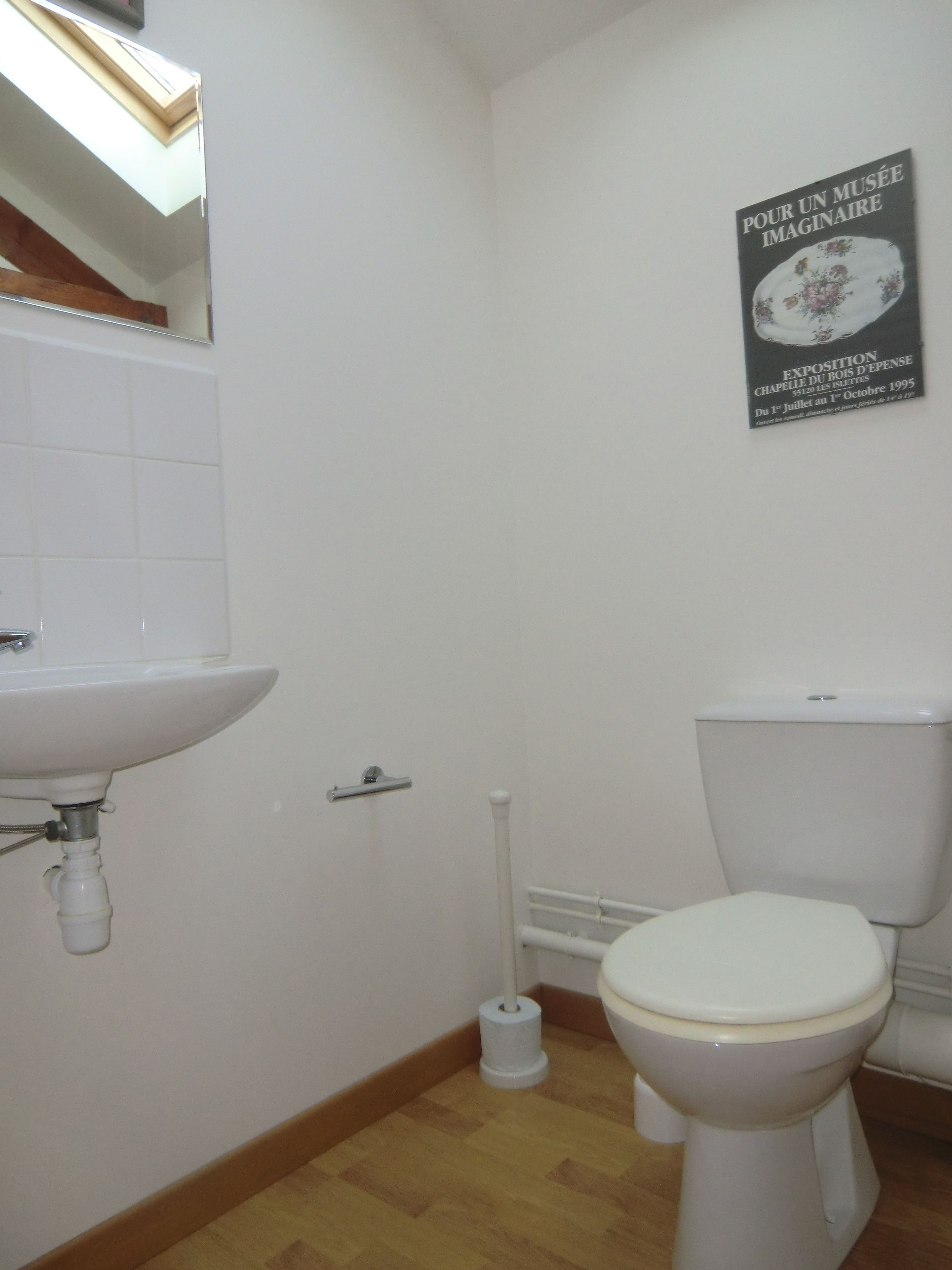 Ein Badezimmer mit einem weißen Waschbecken, einer Toilette und einem Poster an der Wand.