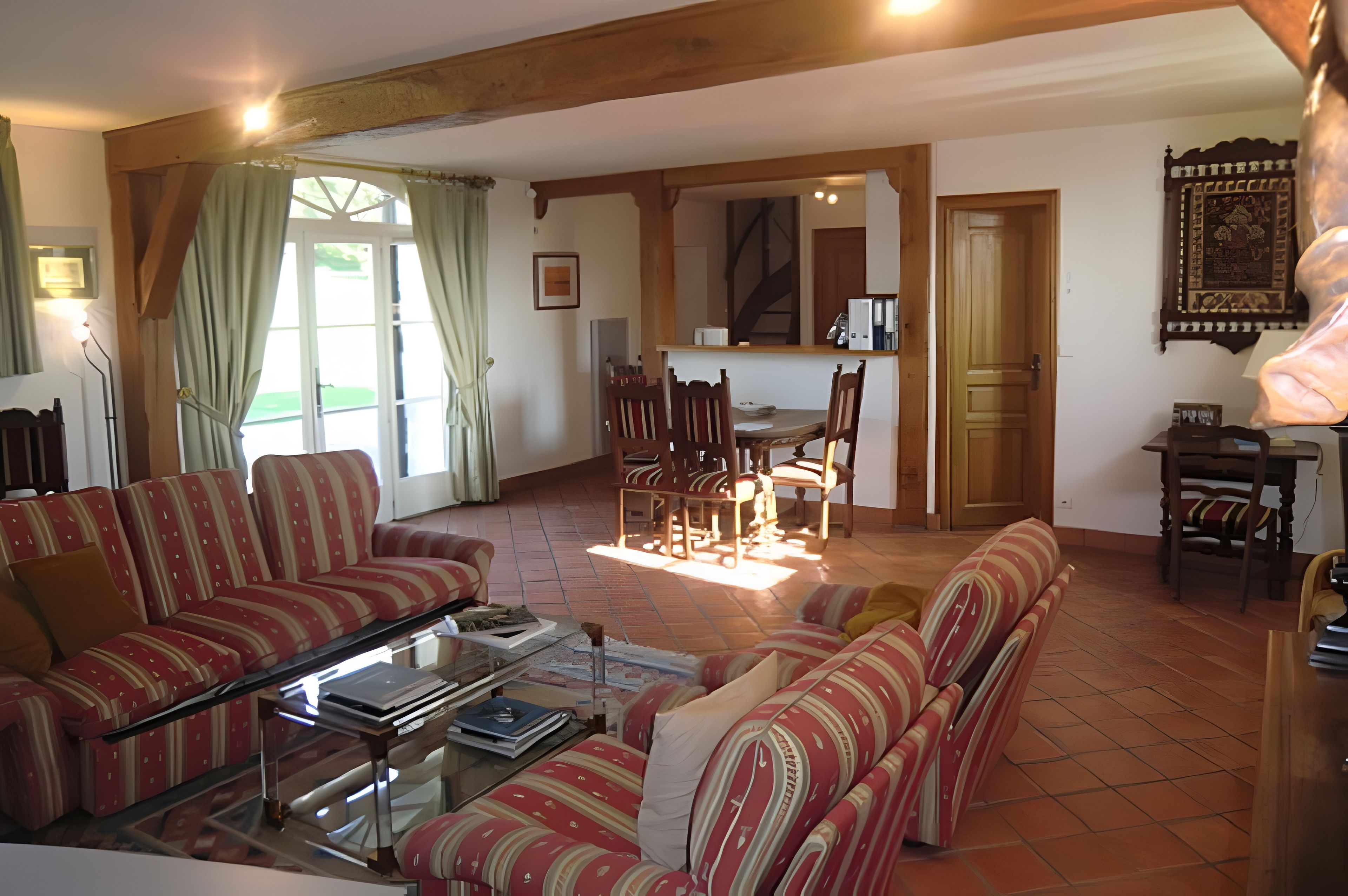 A living room with striped sofas, a coffee table, and a dining area with chairs and a table.