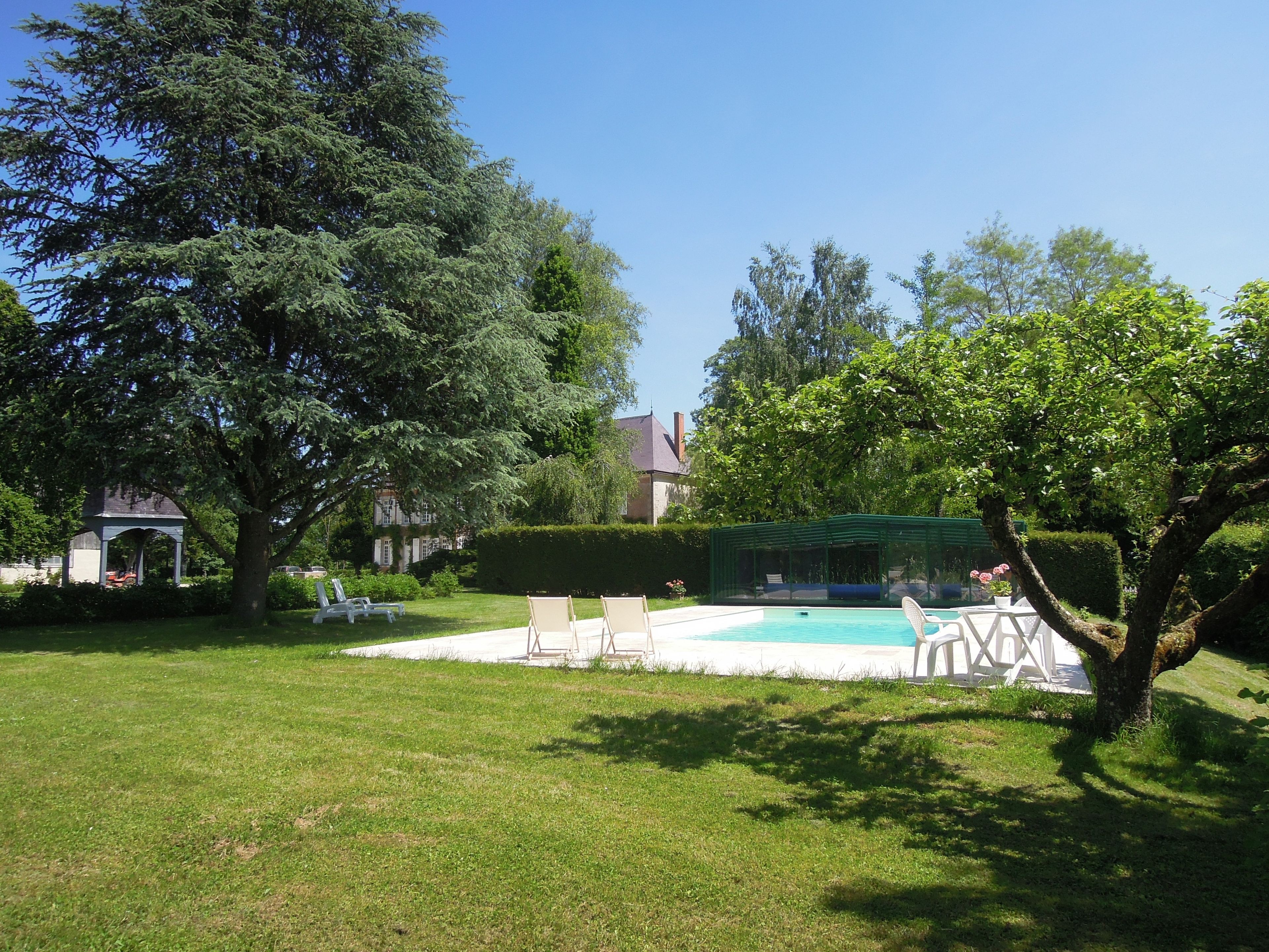 A backyard with a swimming pool, lounge chairs, and a gazebo.