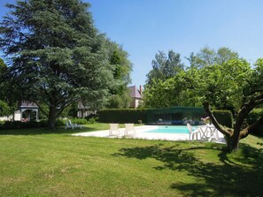 A backyard with a swimming pool, lounge chairs, and a gazebo.
