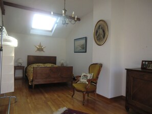 Ein Schlafzimmer mit einem Bett, einem Sessel, einem Schminktisch, einer Stern-Dekoration, einem gerahmten Bild und einer Chandelieber.