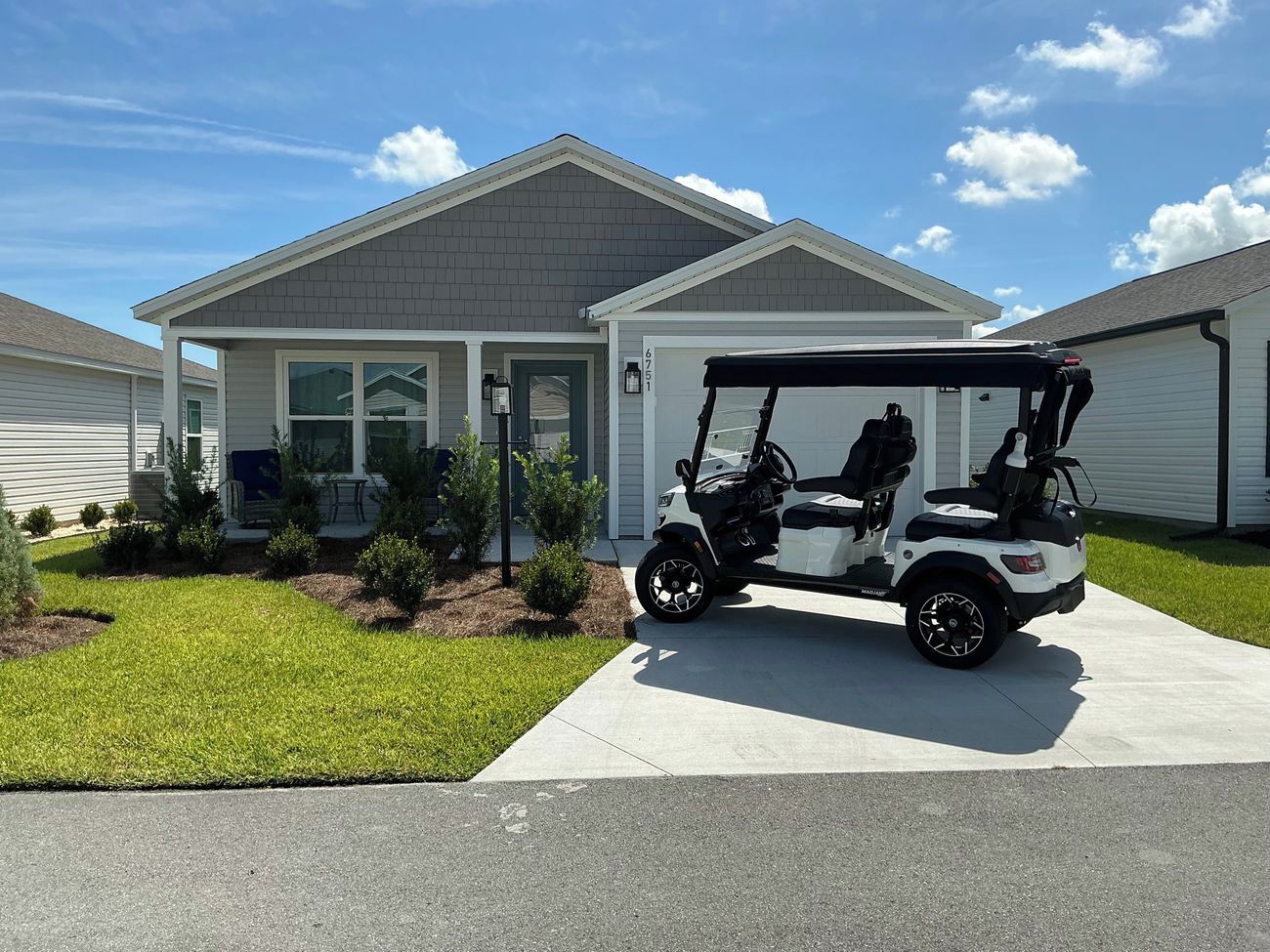 Una casa residencial con entrada para coches, un carrito de golf y un césped bien cuidado.
