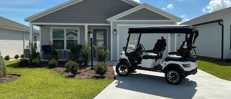 Una casa residencial con entrada para coches, un carrito de golf y un césped bien cuidado.