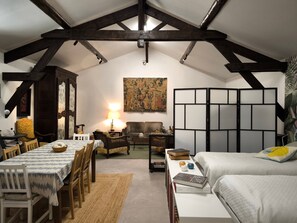 A cozy room with a dining table, chairs, a sofa, a bookshelf, and a decorative lamp.