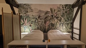 Quarto com cama, estante de livros e um mural com tema de selva.