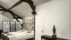 Quarto com cama, estante, escrivaninha e um mural tropical na parede.