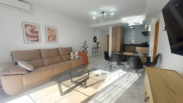 Una sala moderna con un sofá, una mesa de centro y un comedor con sillas.