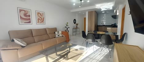 A modern living room with a sofa, coffee table, and dining area with chairs.