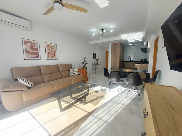 Un salon moderne comprenant un canapé, une table basse et un coin repas avec des chaises.