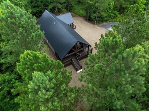 Eine Holzhütte mit einem Metall-Dach, umgeben von dichtem Wald.