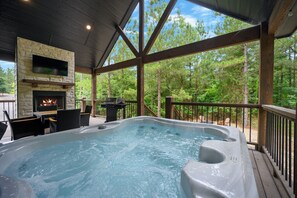 A hot tub with a stone fireplace and outdoor furniture. - 1BR Secluded Hot Tub Retreat (Broken Bow)
