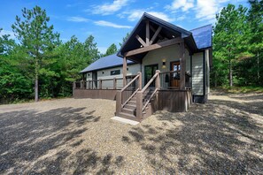 A two-story building with a covered porch and a staircase leading to the entrance. - 1BR Secluded Hot Tub Retreat (Broken Bow)