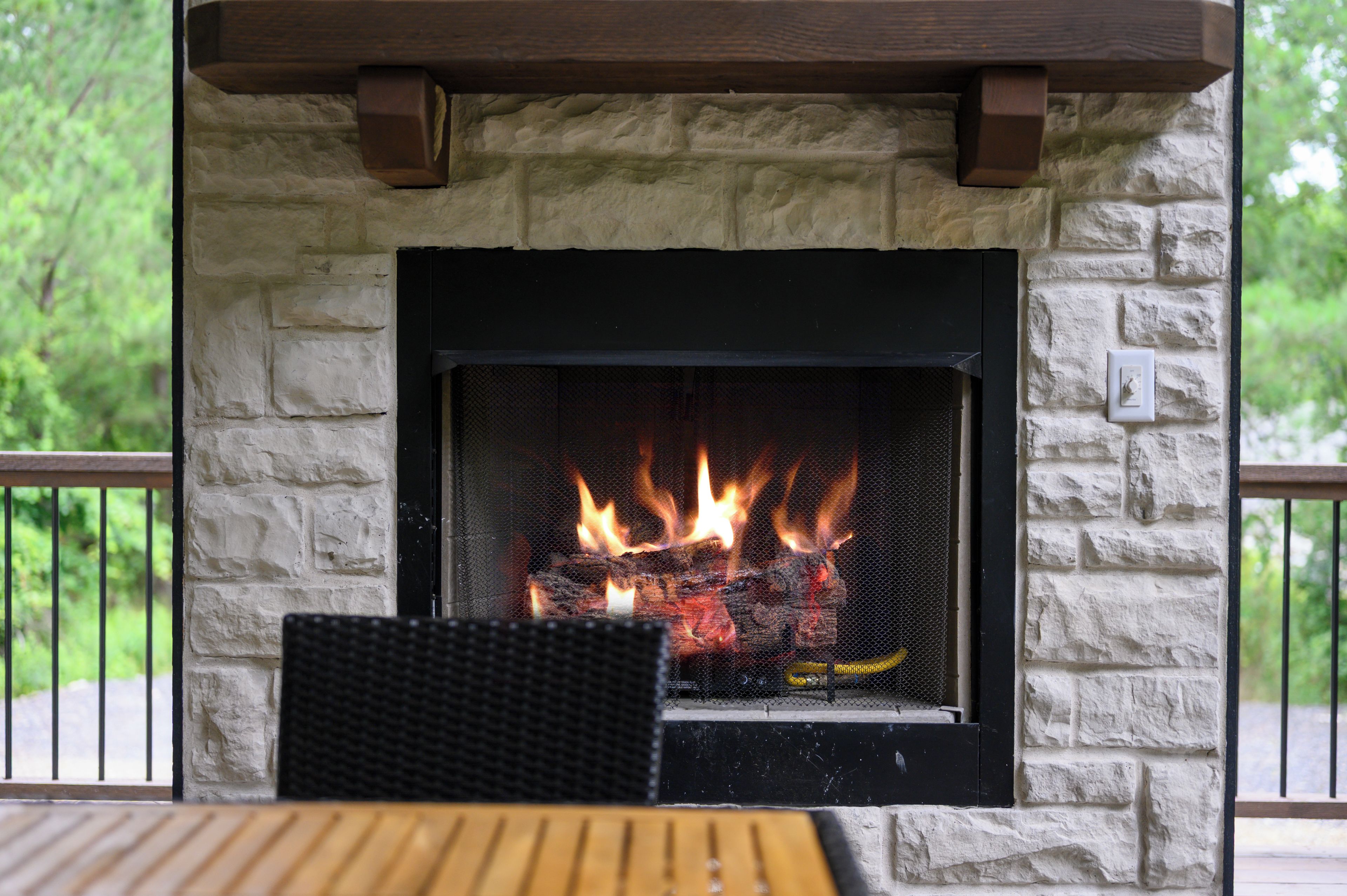 A stone fireplace with a black frame, a mesh screen, and a visible fire.