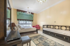 A bedroom with a bed, a desk, a chair, a small table, a rug, and a window with curtains. - Bloomfields 2BR+Maid in Mina Fajer-Fujairah (Dibba Al-Fujairah)