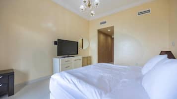 Une chambre d’hôtel avec un lit, une télévision, une commode et un lustre.
