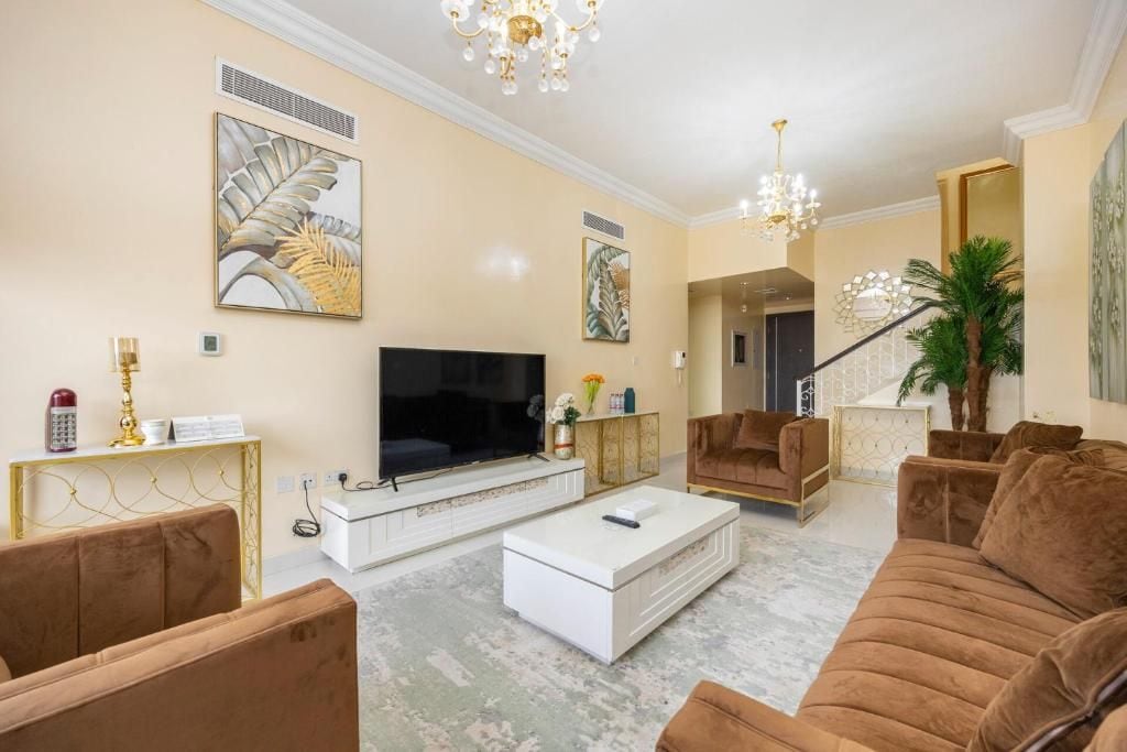 Een moderne woonkamer met een grote flatscreen televisie, een witte salontafel en bruine banken.