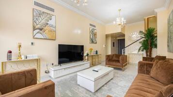 Een moderne woonkamer met een grote flatscreen televisie, een witte salontafel en bruine banken.