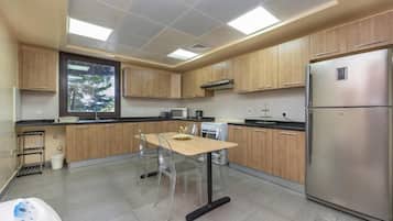 A modern kitchen with wooden cabinets, a stainless steel refrigerator, and a dining area with a table and chairs.