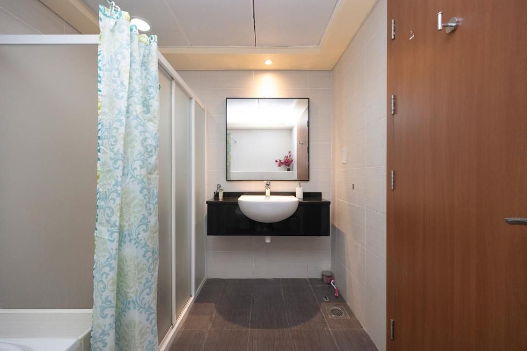 Un baño con ducha, lavabo y espejo.