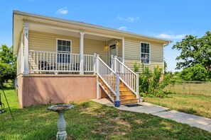 Einbungalow mit einer Veranda, einer Treppe zum Eingang und einem kleinen Garten.