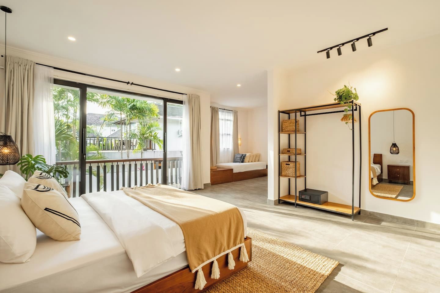 Une chambre moderne avec un grand lit, un balcon, un dressing et un miroir.