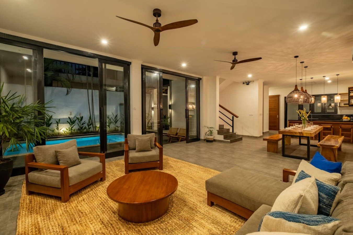 Uma sala de estar moderna com piscina, espaço para sentar e escada que leva a um andar superior.