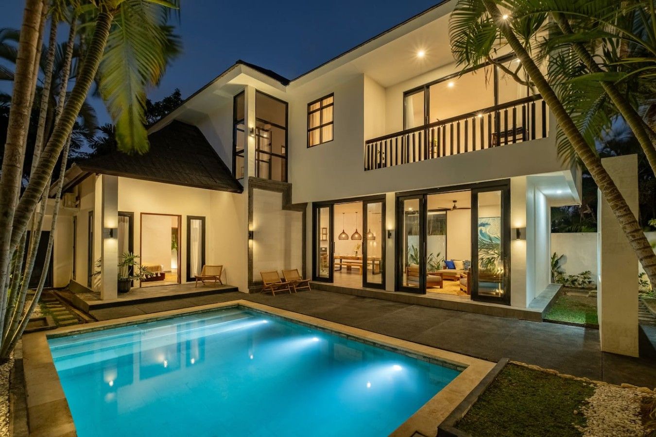A modern two-story house with a swimming pool, large windows, and a balcony.
