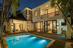 Une maison moderne à deux étages, dotée d’une piscine, de grandes fenêtres et d’un balcon.
