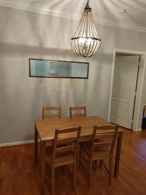 A dining area with a wooden table and chairs, a hanging light fixture, and a mirror on the wall. - Med Center Condo With Pool Gym and Balcony (Houston)