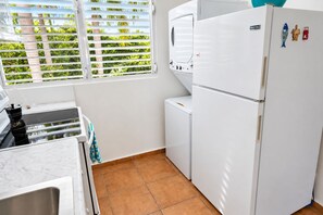 Eine Küche mit einem weißen Kühlschrank, einem Herd und einem Fenster mit Jalousien.