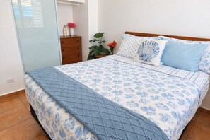 Ein Schlafzimmer mit einem Bett, einem Nachttisch, einer Kommode und einer Zimmerpflanze.
