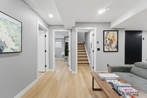 A modern living room with a grey sofa, a coffee table, and a staircase leading to another room. - Mountain Escape Deluxe King Suite (Free Parking) (Cochrane)
