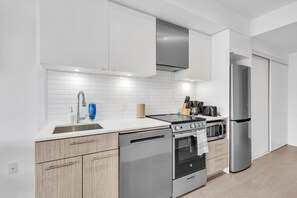 Een moderne keuken met witte kastjes, roestvrijstalen apparatuur en een betegelde spatwand.