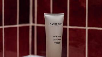 Un tube de crème coiffante de la marque Sachajuan, une brosse à dents et un savon, le tout posé sur un plateau.