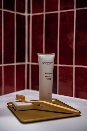 A tube of Sachajuan styling cream, a toothbrush, and a bar of soap on a tray. - The House of Delray (Tel Aviv)