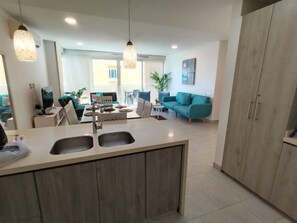 A modern kitchen with a central island, a dining area with a table and chairs, and a living room with a sofa and a plant. - Inspiration from the Sea (Cartagena)