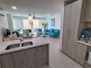 A modern kitchen with a central island, a dining area with a table and chairs, and a living room with a sofa and a plant. - Inspiration from the Sea   (Cartagena)