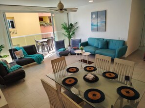 A modern living room with a glass dining table, sofas, and a ceiling fan. - Inspiration from the Sea   (Cartagena)
