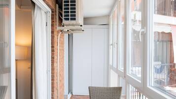 Un balcon avec une table et des chaises, un appareil de climatisation et une vue sur l’extérieur.