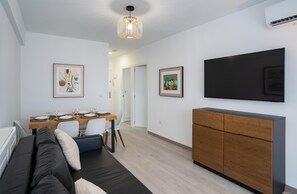 Un salon moderne avec un canapé, une table à manger et des œuvres d’art accrochées aux murs.