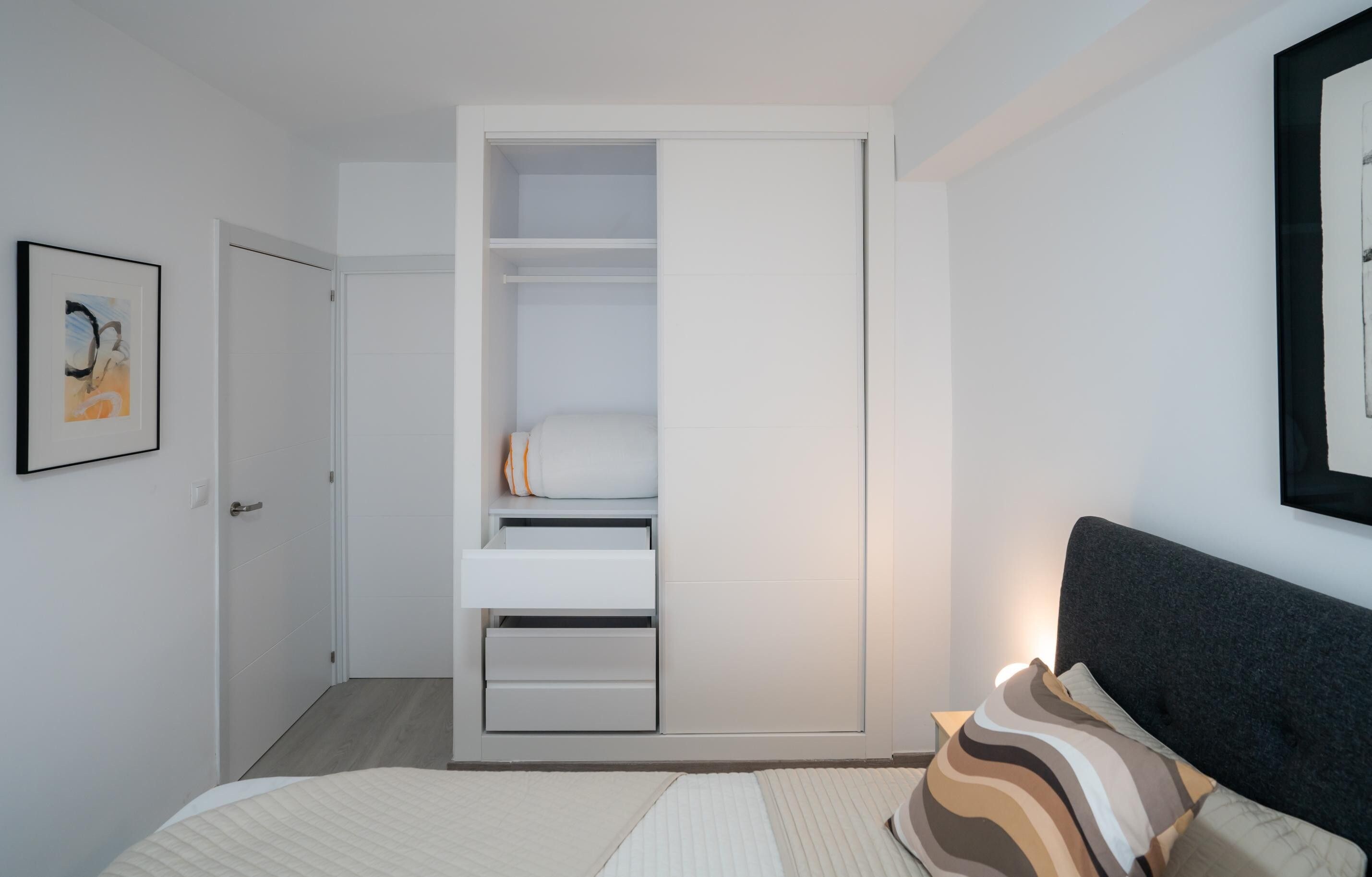 Une chambre à coucher avec un lit, une table de chevet, une armoire et un tableau encadré au mur.