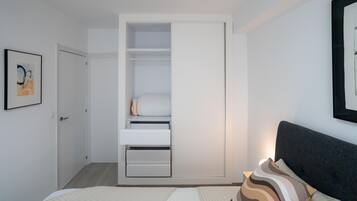 Une chambre à coucher avec un lit, une table de chevet, une armoire et un tableau encadré au mur.