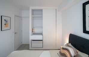 Une chambre à coucher avec un lit, une table de chevet, une armoire et un tableau encadré au mur.