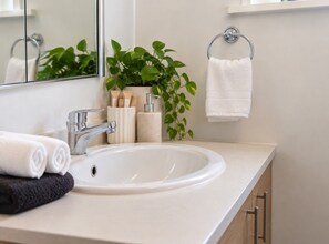 A bathroom with a white sink, a mirror, a towel rack, and a potted plant. - Chic St Kilda retreat with secure parking (St Kilda)