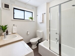 A modern bathroom with a toilet, sink, and bathtub. - Chic St Kilda retreat with secure parking (St Kilda)