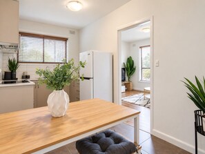 A modern kitchen with a wooden table, a white vase with green plants, and a refrigerator. - Chic St Kilda retreat with secure parking (St Kilda)